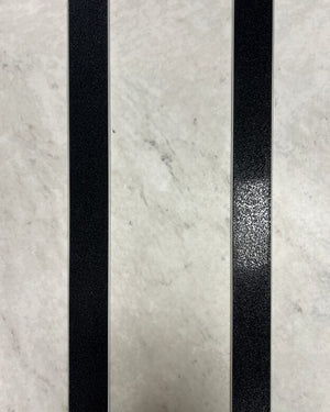 Taktila ledstavslist med svart ilägg installerade på ett vitt marmorgolv.