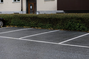 Parkeringsplatser med tydlig vit Safestep Linjemålning intill häck och bostadsfastighet.