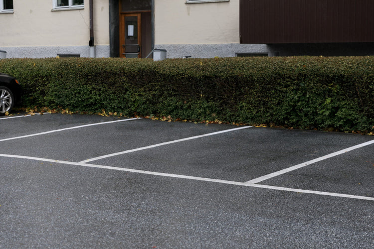 Parkeringsplatser med tydlig vit Safestep Linjemålning intill häck och bostadsfastighet.