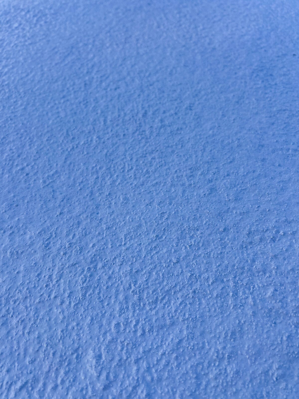 är en extrem närbild av den texturerade blå halkskyddsfärgen som visar dess korniga, granulatfyllda struktur.