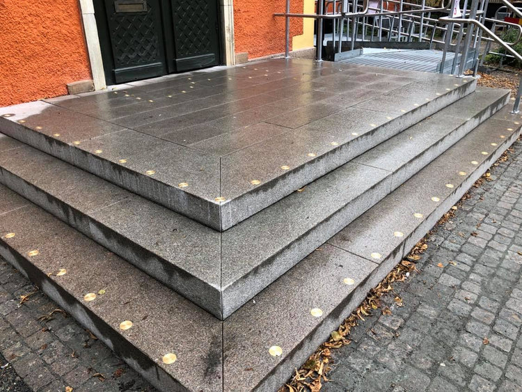 Trappa med ljusa kontrastmarkeringar längs framkanten av varje steg som leder upp till en orange byggnad 