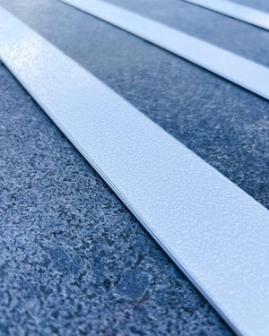 Taktil ledstavslist med vitt ilägg i ljus aluminiumprofil ger kontrast och halkskydd på blågrått golv.