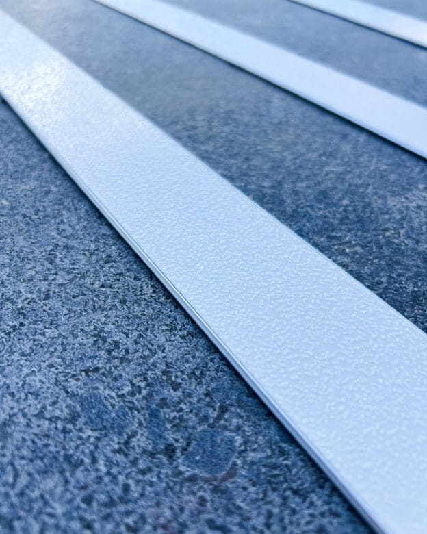 Taktil ledstavslist med vitt ilägg i ljus aluminiumprofil ger kontrast och halkskydd på blågrått golv.