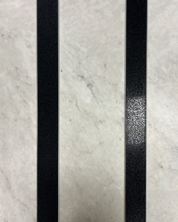 Taktila ledstavslist med svart ilägg installerade på ett vitt marmorgolv.