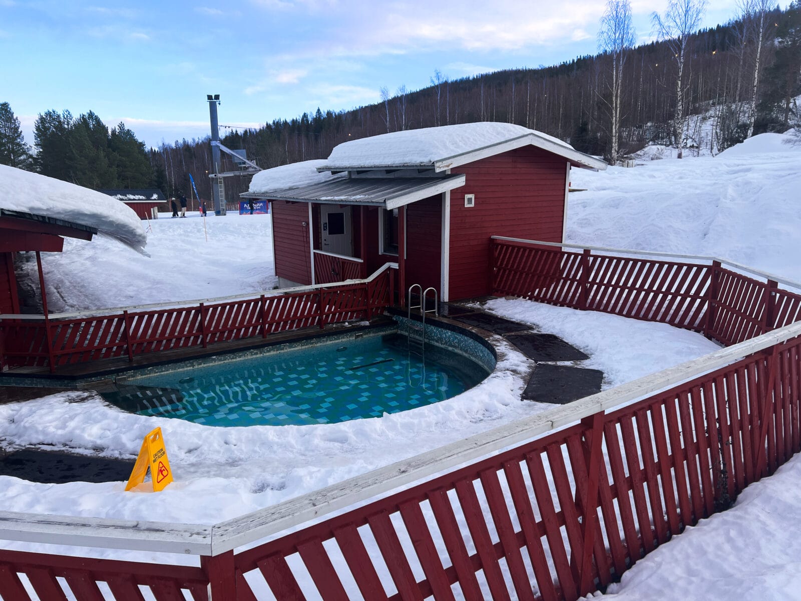 Svarta värmemattor som skapar en snöfri passage runt en utomhuspool under vintersäsong.